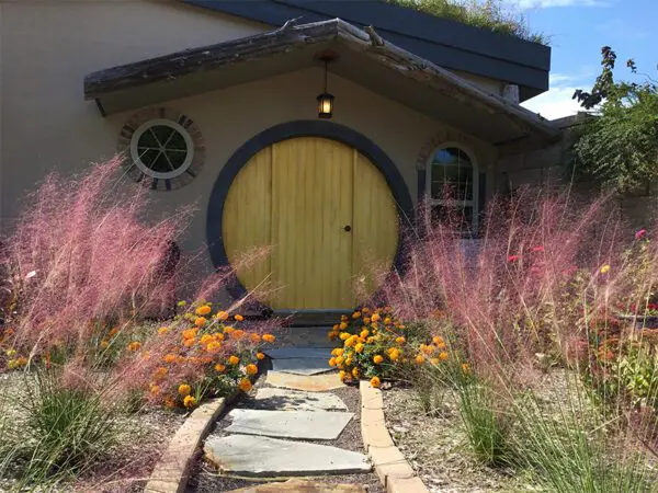 A yellow door and some pink flowers in front of a house.