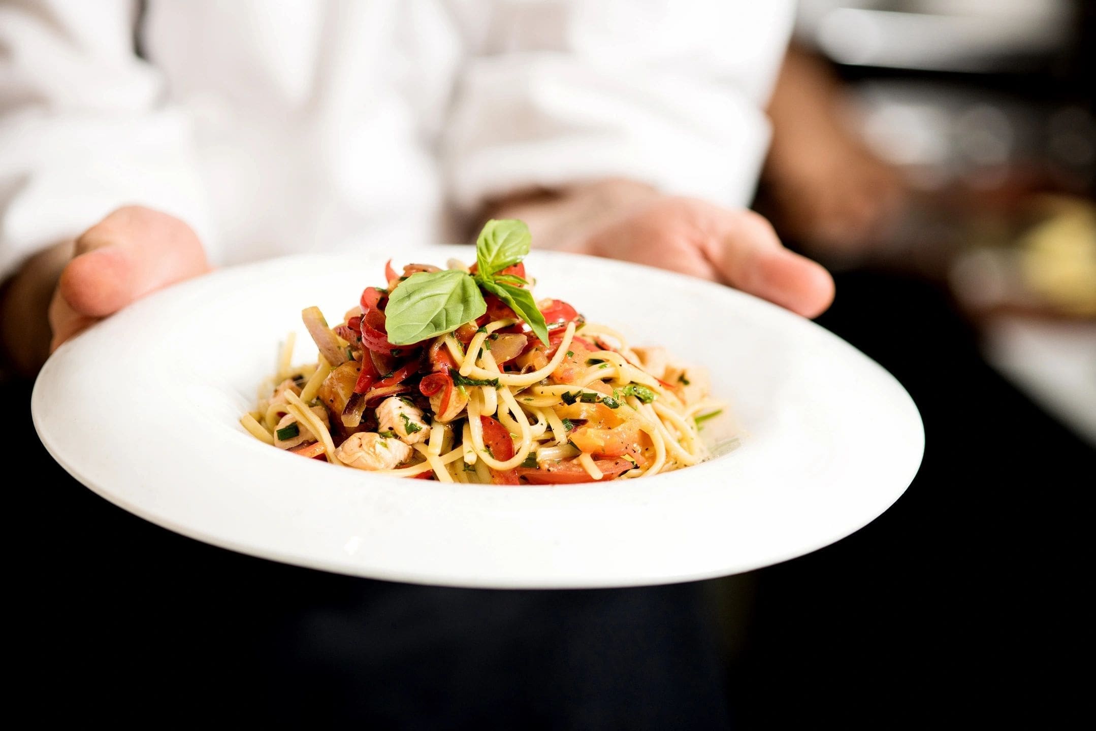 A person holding onto a plate of pasta