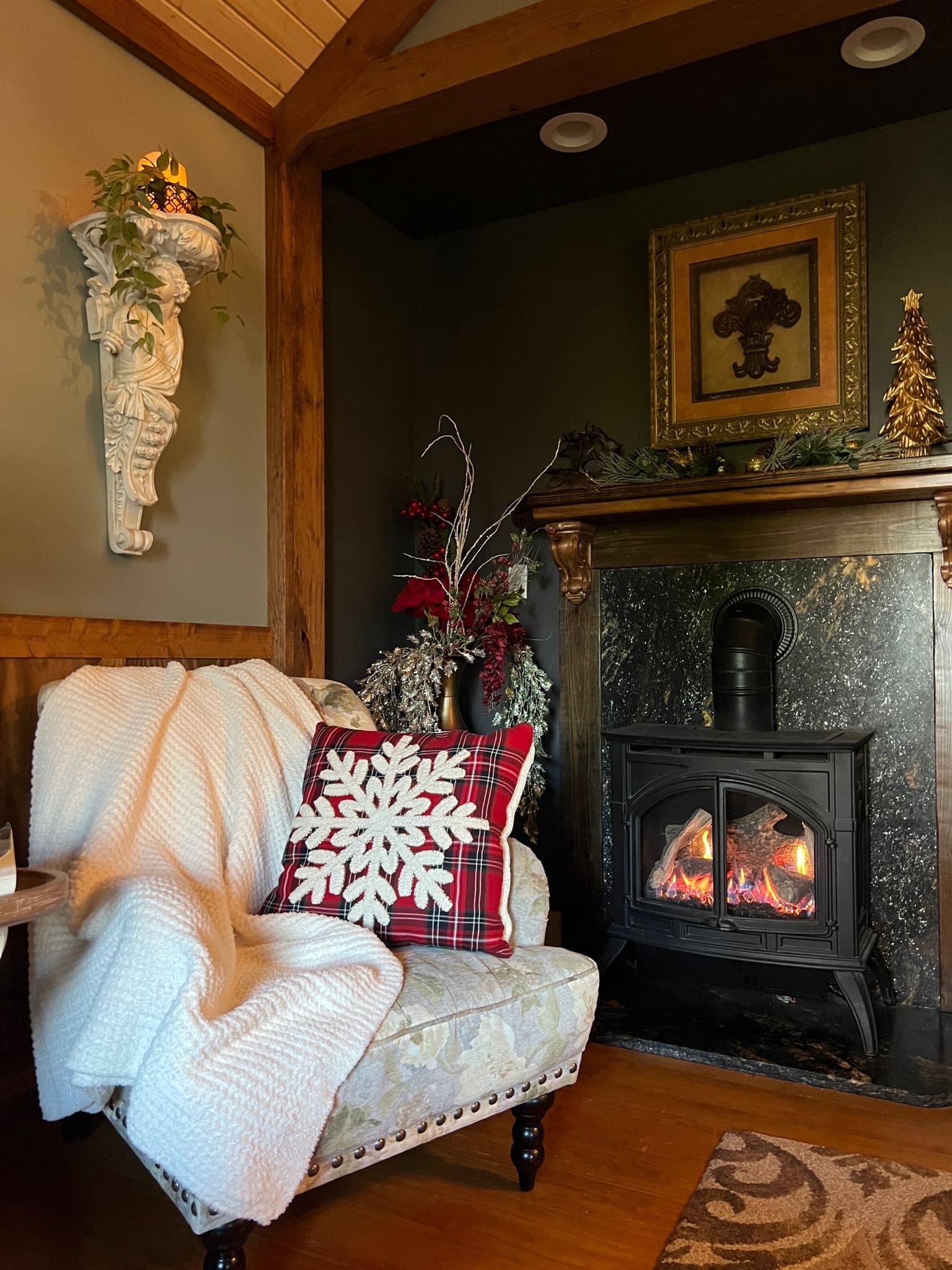 Cozy chair with Christmas decor pillow, soft blanket, and fireplace.